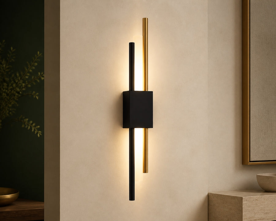 The linear black and gold sconce lit on a wall