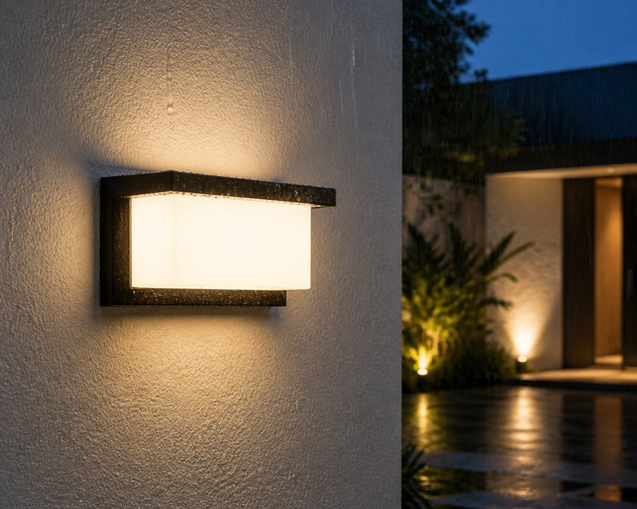 The outdoor wall light glowing on an exterior wall in the rain