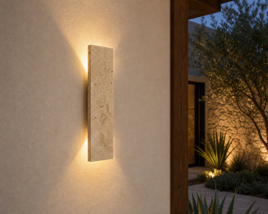 The sconce washing warm light up and down an exterior wall