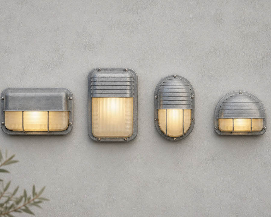Four of the bulkhead profiles on a pale wall, each with a hooded top and cage bars over ribbed frosted glass