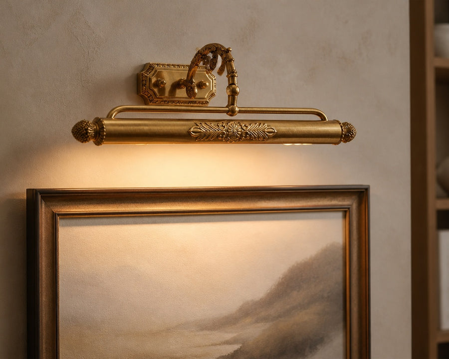 Brass swing-arm picture light washing a framed print in warm light